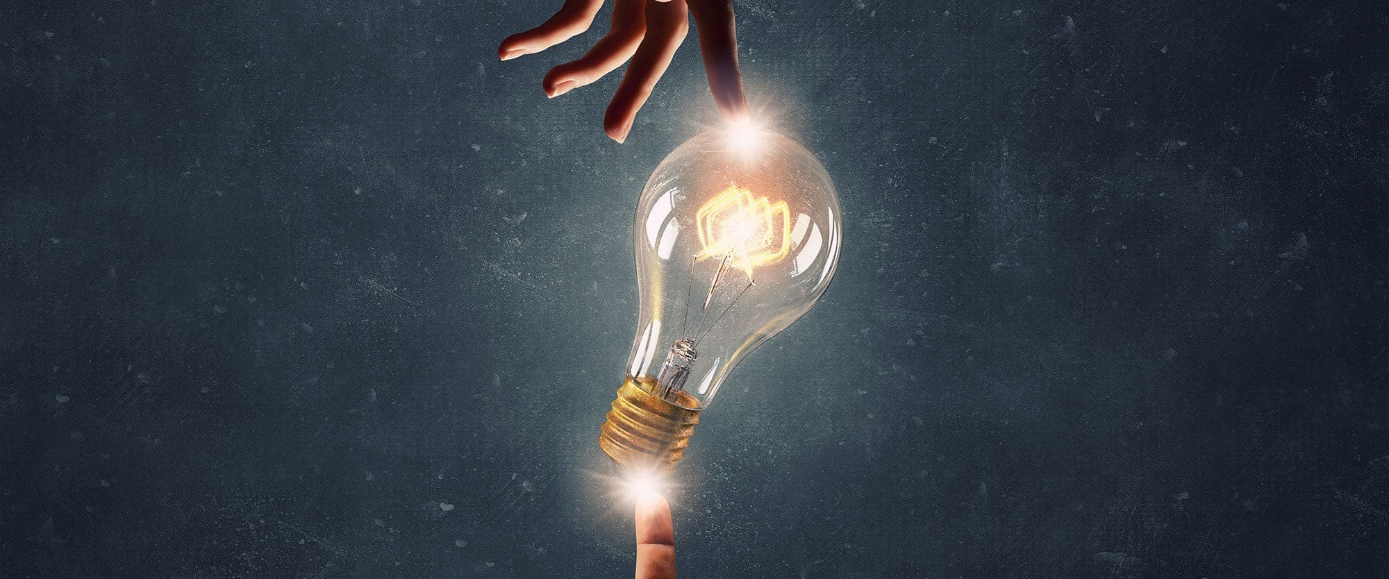 A hand reaching towards a glowing light bulb, symbolizing ideas.