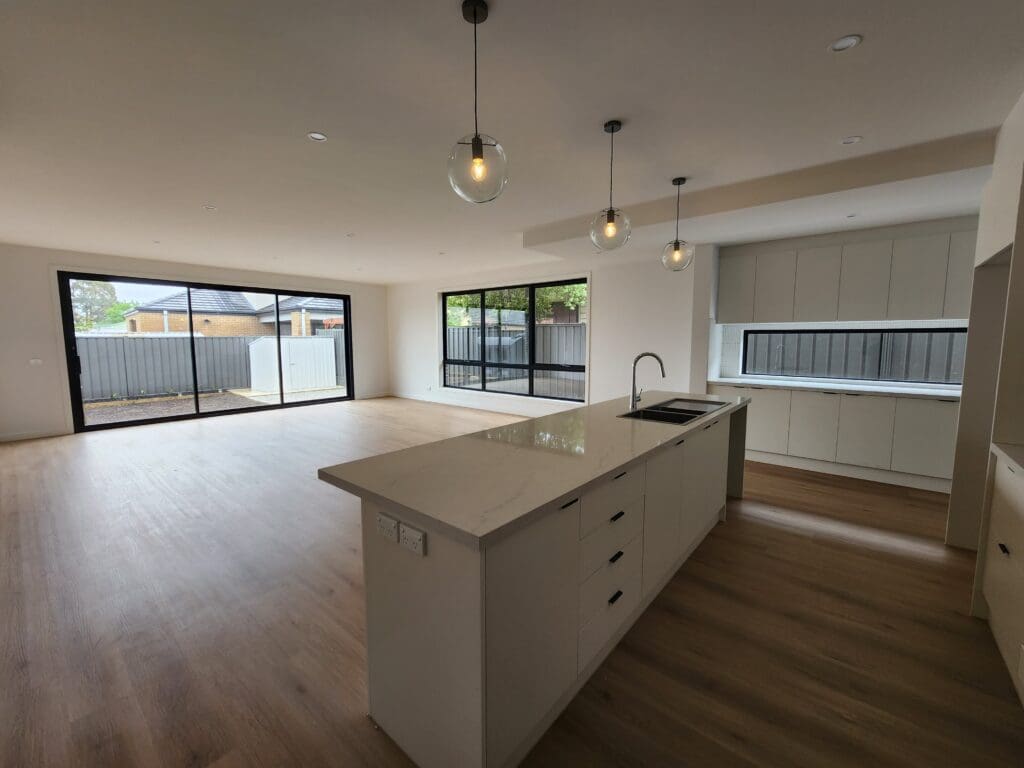 Modern kitchen and living room with large windows and natural light.